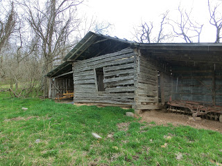 One room cabin with livestock shelter attached to the sides.